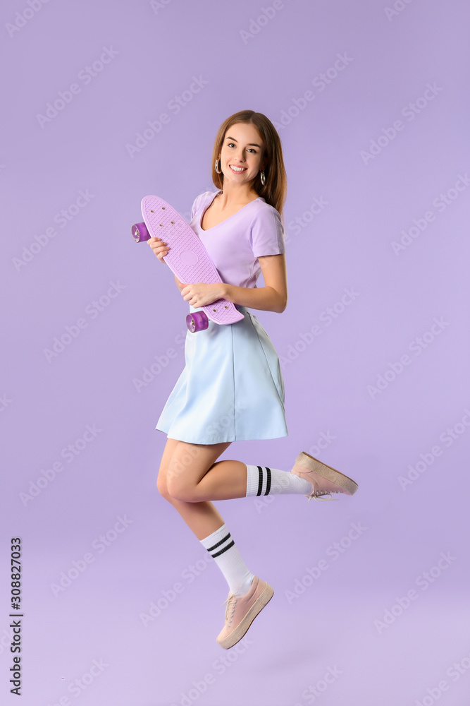 Jumping hipster girl with skateboard on color background