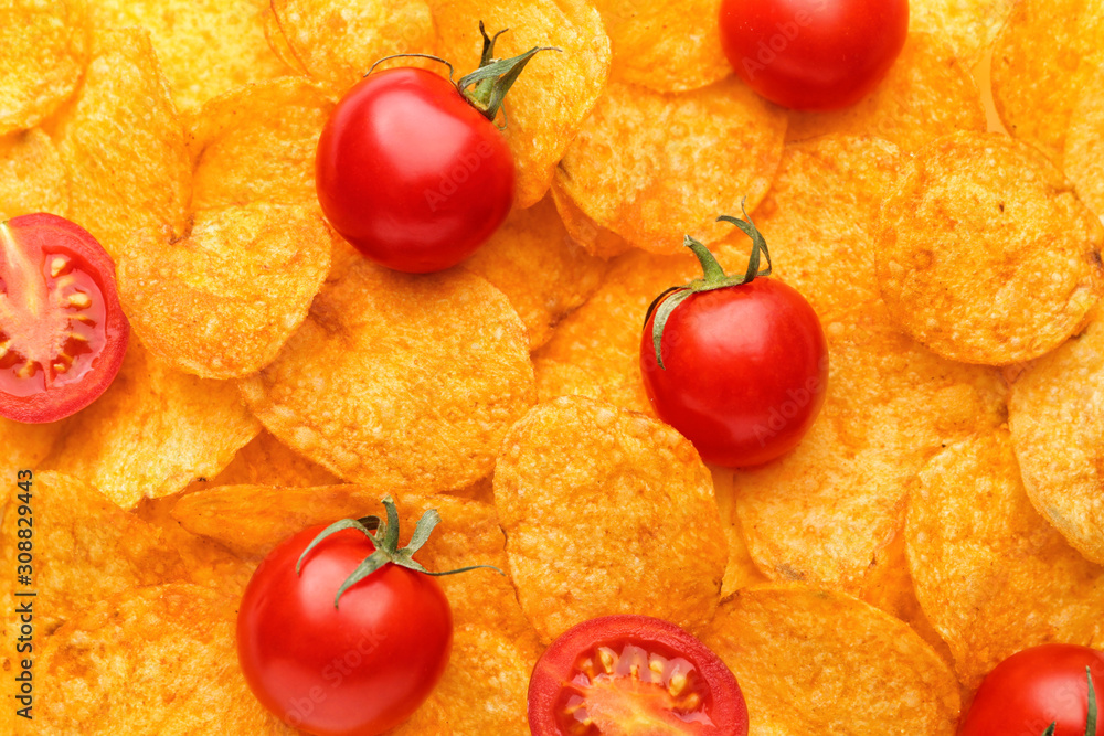 Tasty potato chips with tomatoes as background