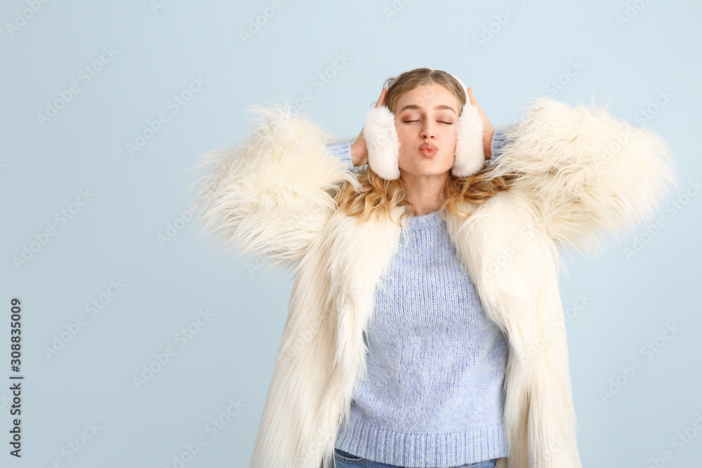 Happy young woman in winter clothes on color background