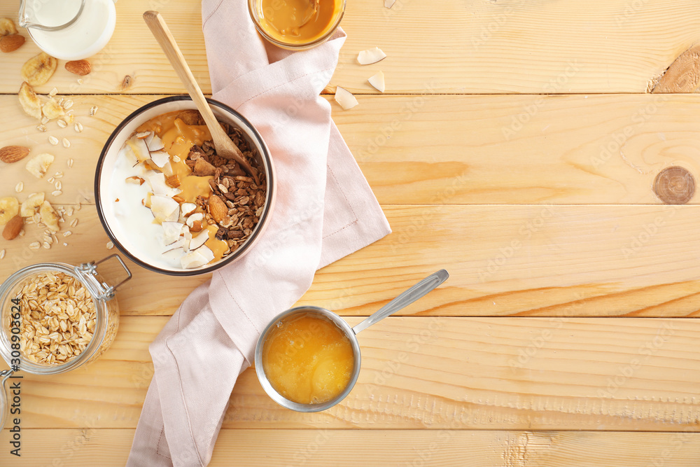 Tasty granola with yogurt in bowl on wooden table