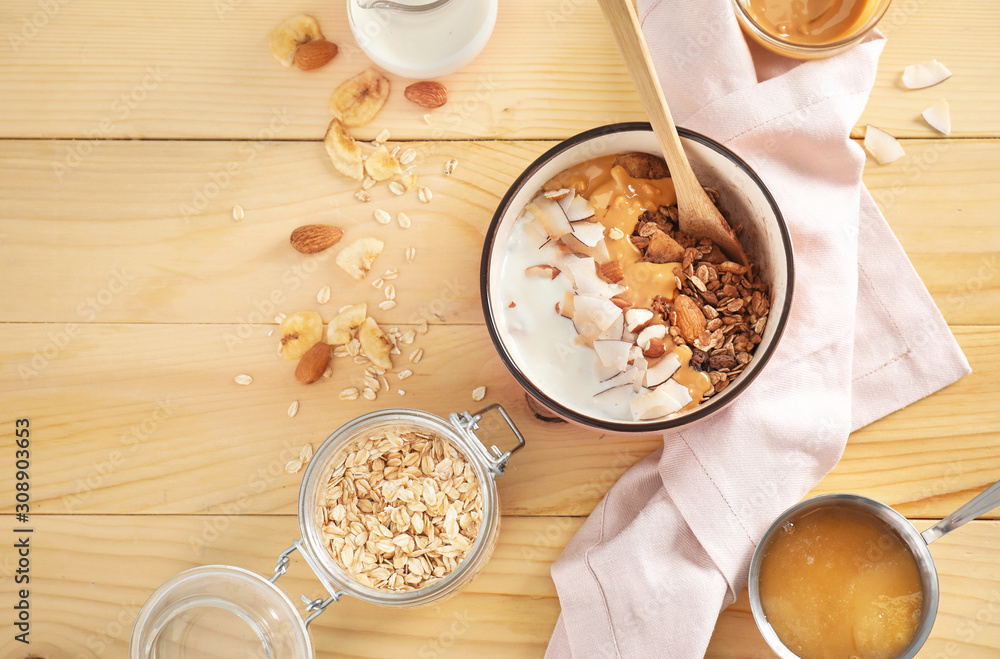 Tasty granola with yogurt in bowl on wooden table