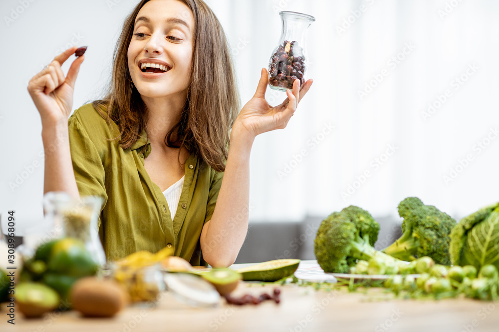 一个年轻快乐的女人的画像，桌上摆着干玫瑰果和很多健康的绿色食物。C