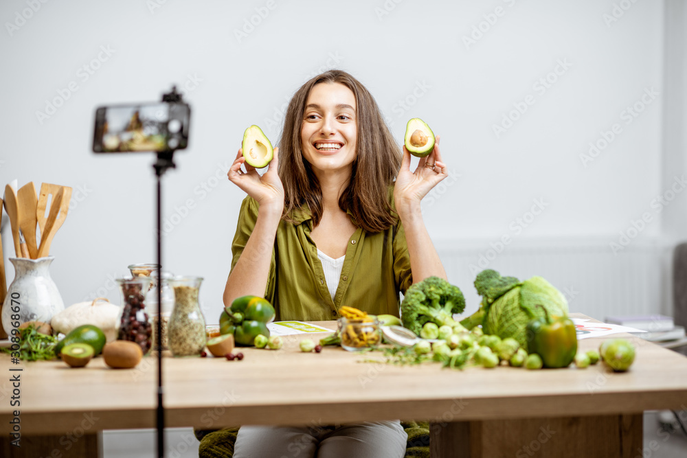 一位年轻女士在智能手机上录制了她关于健康饮食的视频日志。坐在桌子旁。