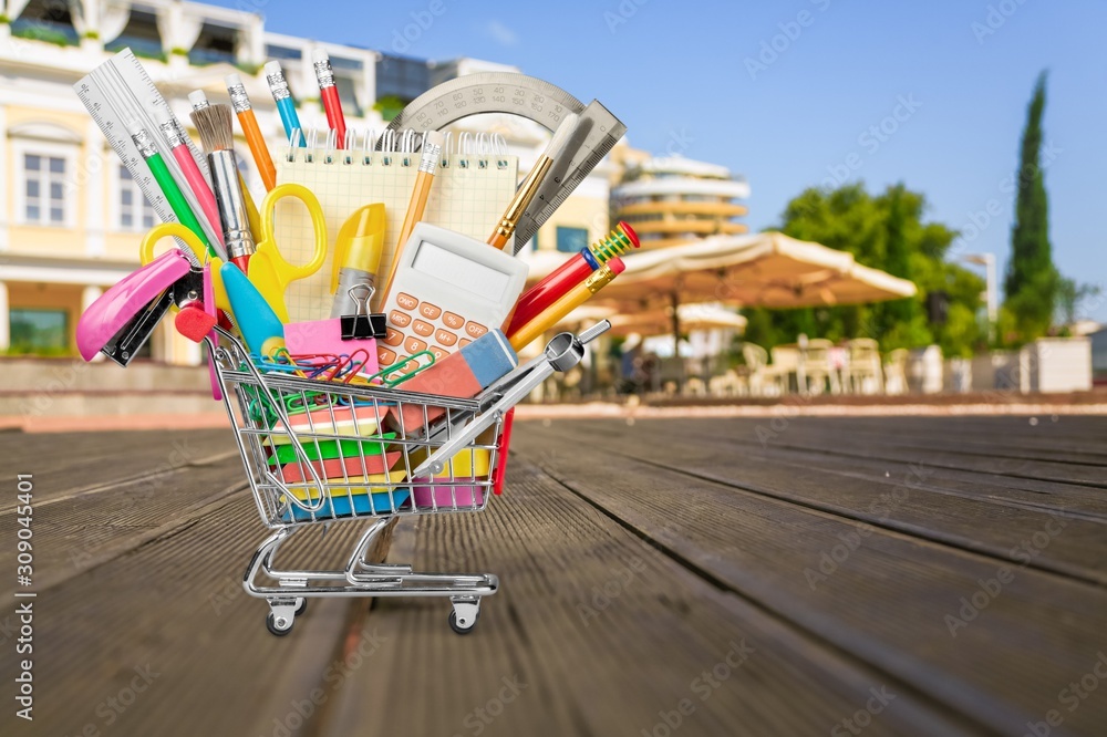 Stationery objects in mini supermarket cart on  background