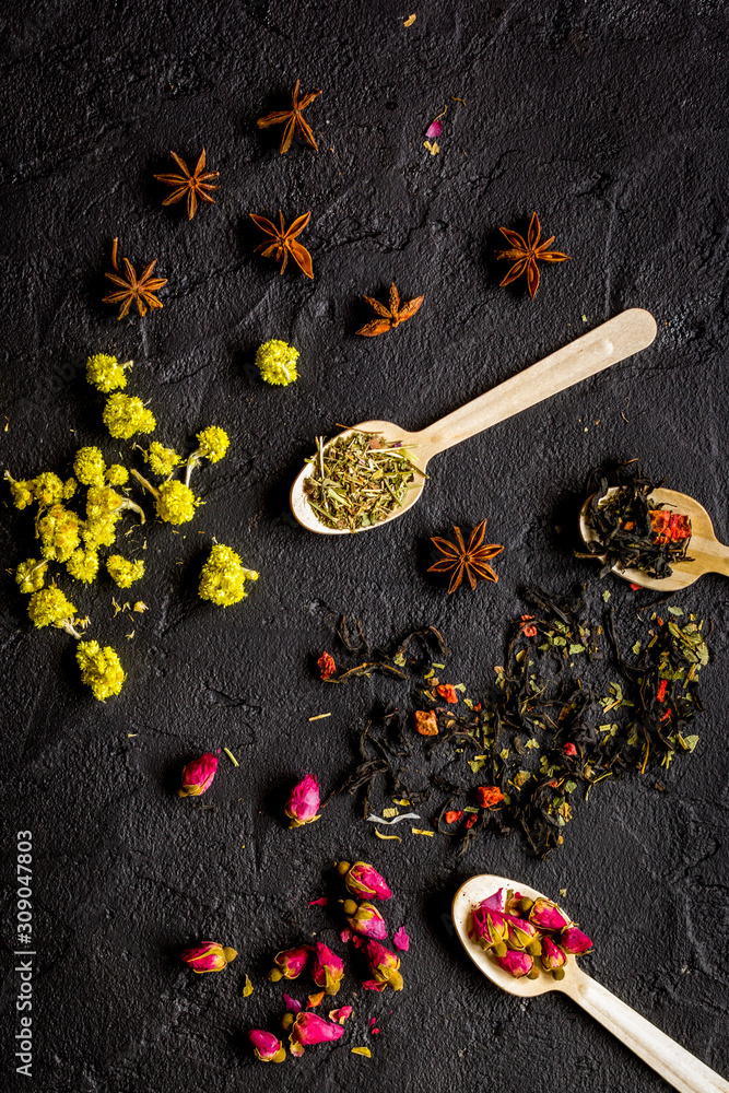 Herbs and spoons on black background top view