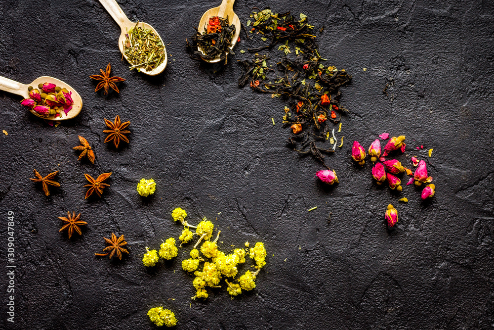 Herbs and spoons on black background top view