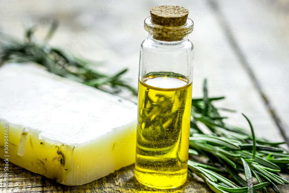 natural cosmetic oil with fresh rosemary and soap on light wooden table background