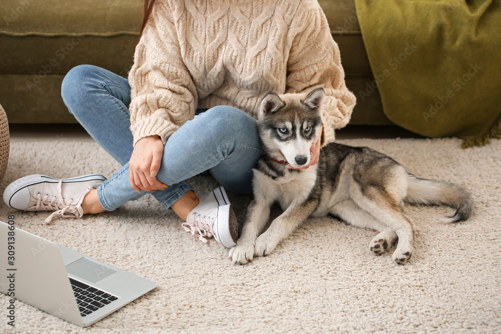 Young woman with funny husky puppy resting at home