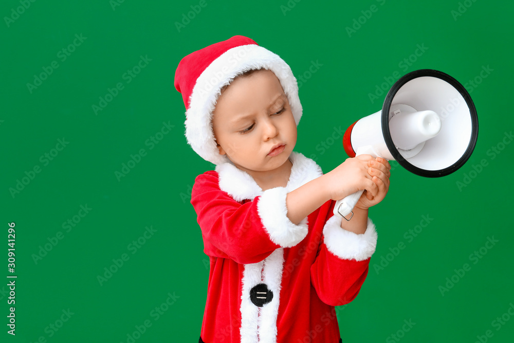 Cute little boy in Santa costume and with megaphone on color background