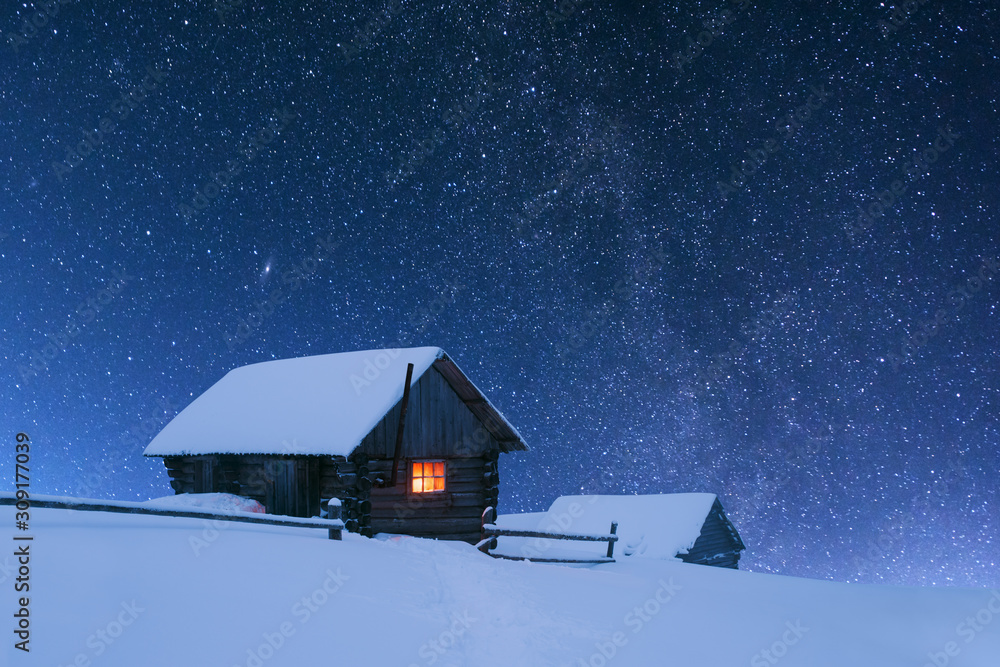 梦幻般的夜景在乳白色的道路上闪闪发光。带着灯光的雪屋的戏剧性冬季场景