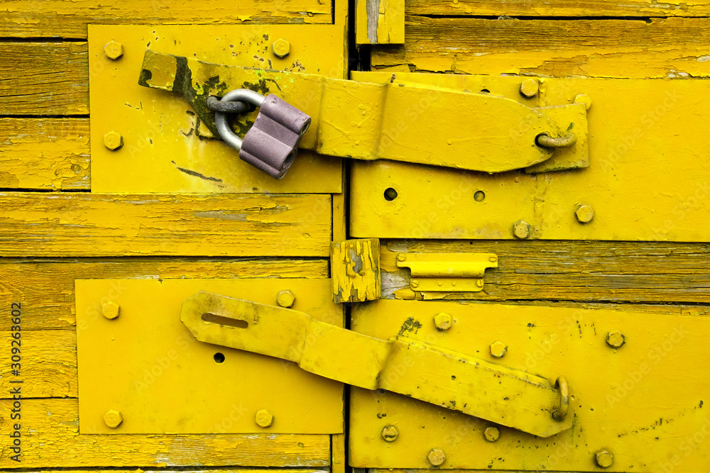 Vivid old yellow wooden locked door texture background. Door with old metal lock. Close up, copy spa