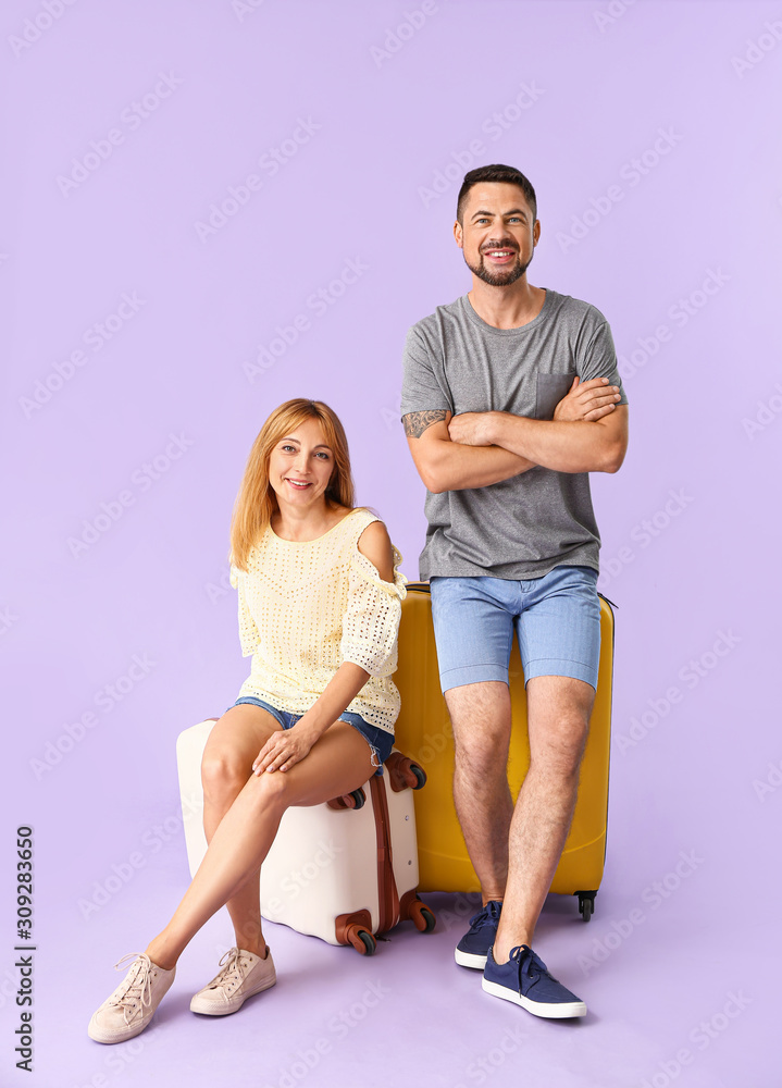 Couple with suitcases on color background