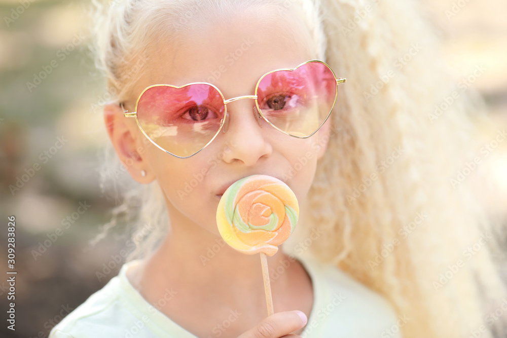 Cute little girl with lollipop outdoors