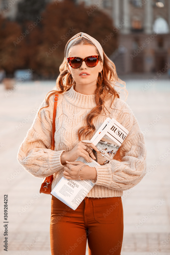 Fashionable young woman with newspaper outdoors