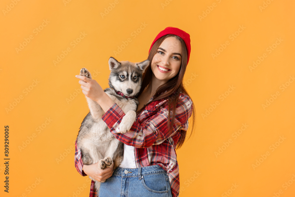 Stylish woman with funny husky puppy on color background