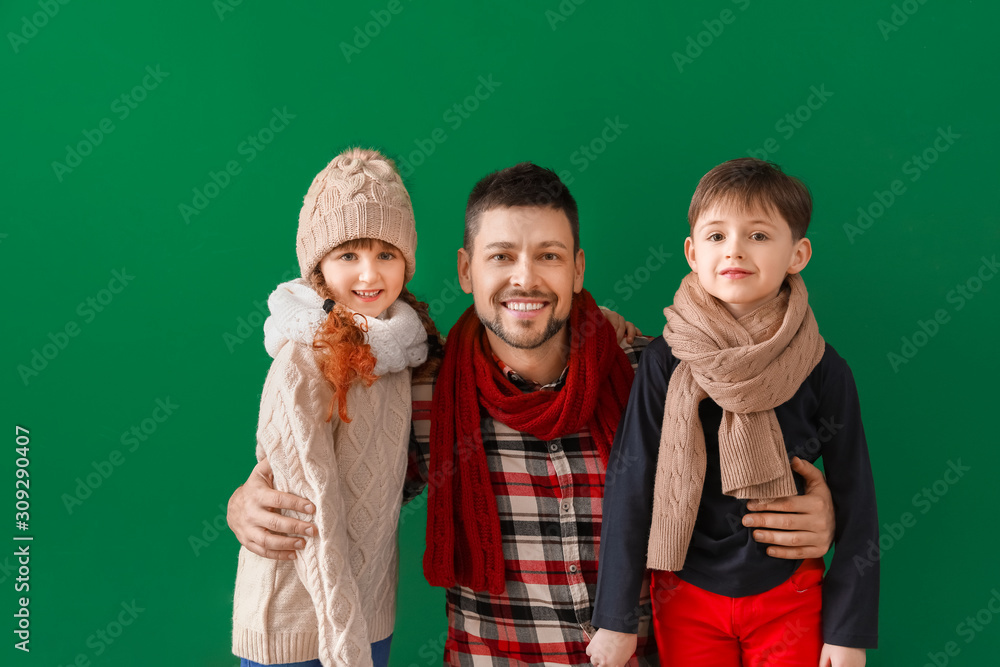 Happy family in winter clothes on color background