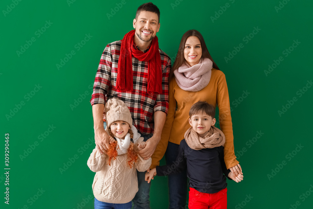 Happy family in winter clothes on color background