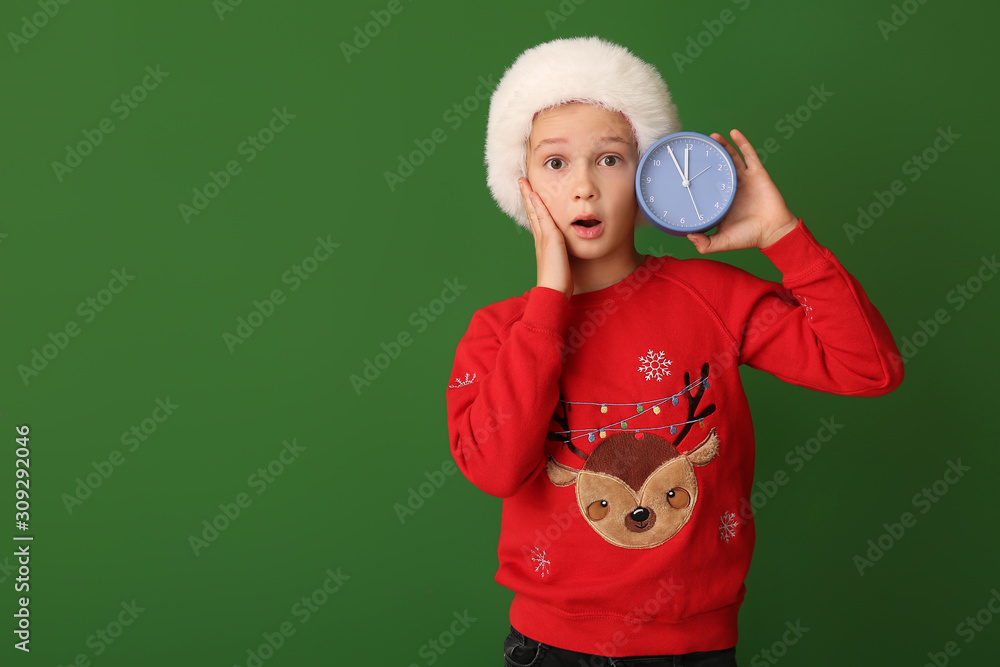 Surprised little boy with alarm clock on color background. Christmas countdown concept