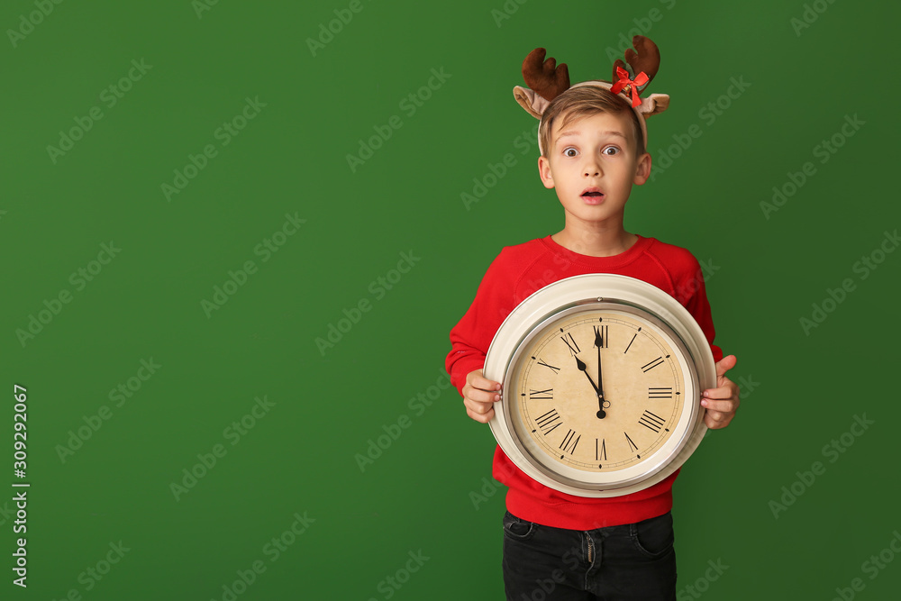 Surprised little boy with clock on color background. Christmas countdown concept