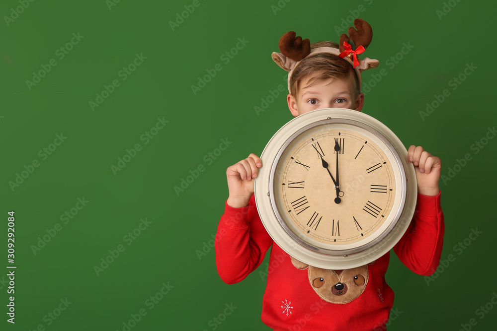 Little boy with clock on color background. Christmas countdown concept