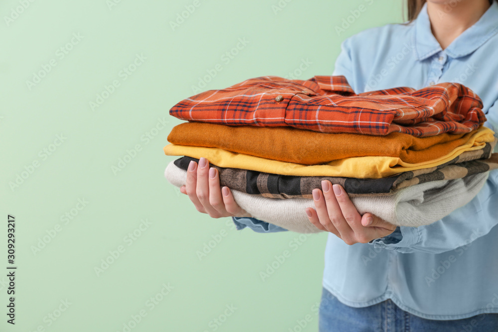 Young woman with clean clothes on color background, closeup