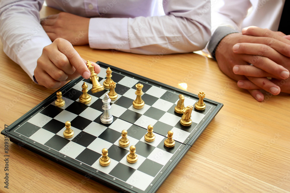 A businessman teaches his friends to play chess,wooden table.