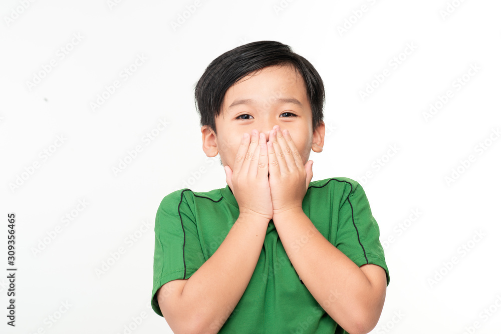 Cute asian boy covers his mouth with his hands.