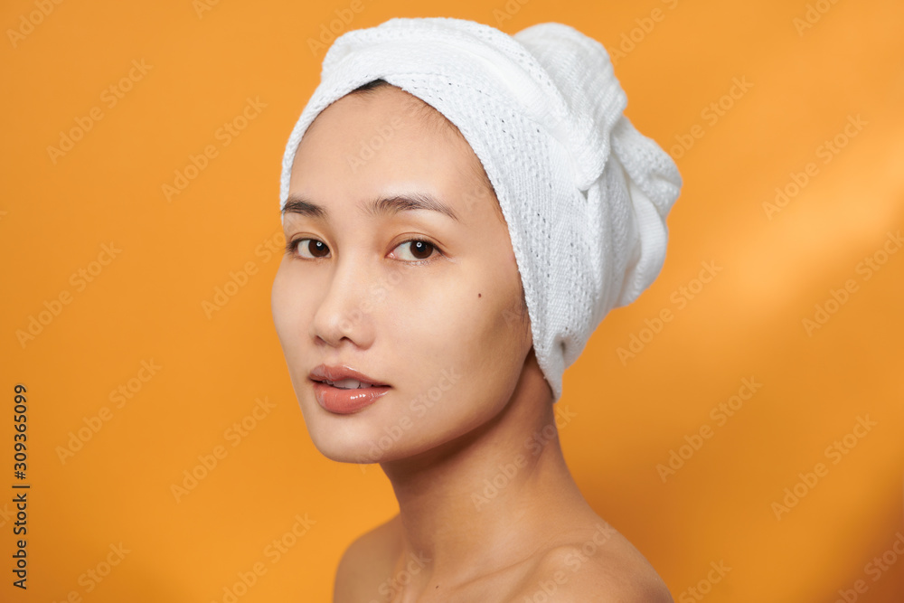 Closeup portrait of attractive smiling Asian woman blond wearing a towel on her head isolated on ora