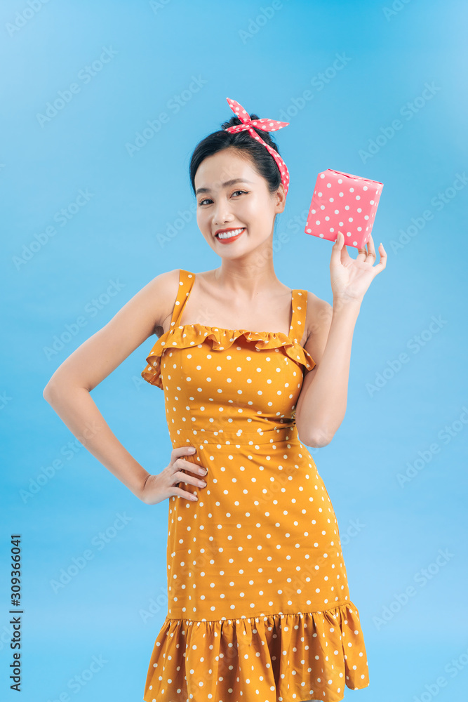 Young woman holding gift box with holiday present isolated on blue background