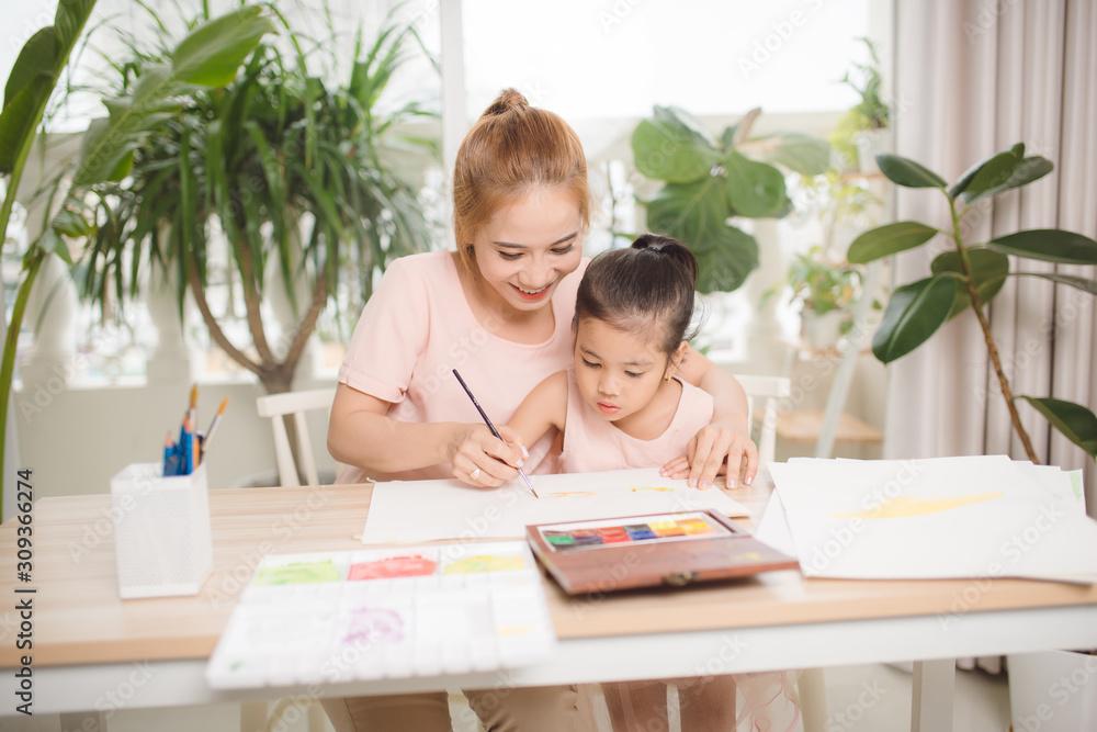 Little girl painting with her mother laying in livingroom