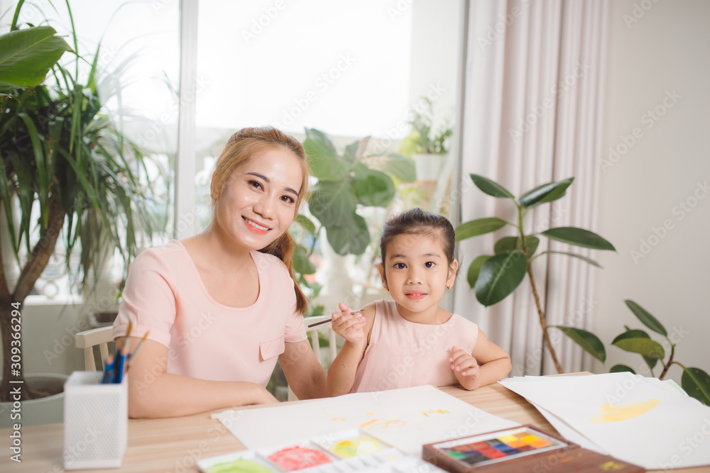 亚洲漂亮的年轻母亲和她的女儿一起给石膏娃娃止痛。