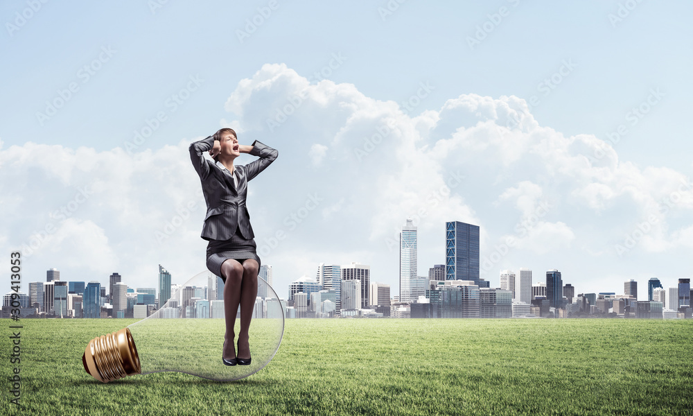 Stressful woman sitting on big light bulb