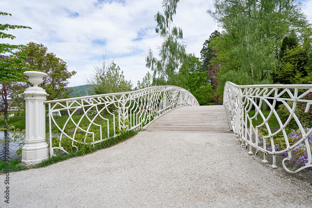 A beautiful white forged iron bridge and its railing in a public park in the European city of Baden 