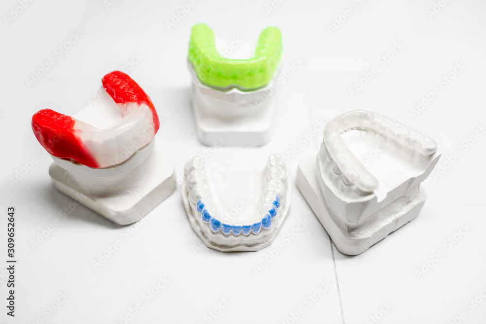 Gypsum models of artificial jaw with dental caps on the white background. Orthodontic caps and boxin