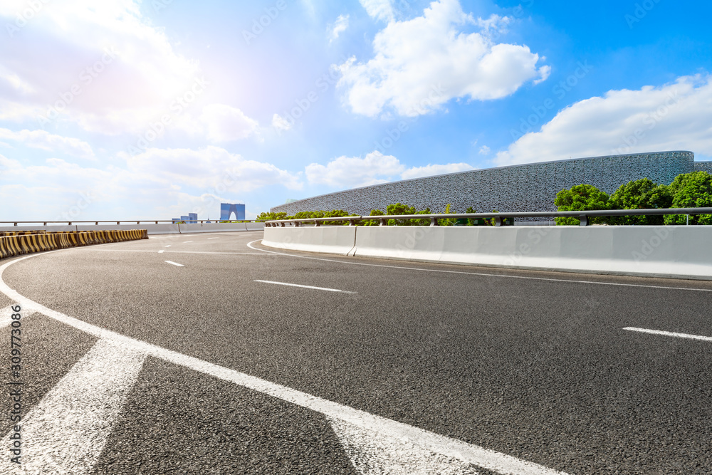 Asphalt highway and Suzhou city skyline on a sunny day.