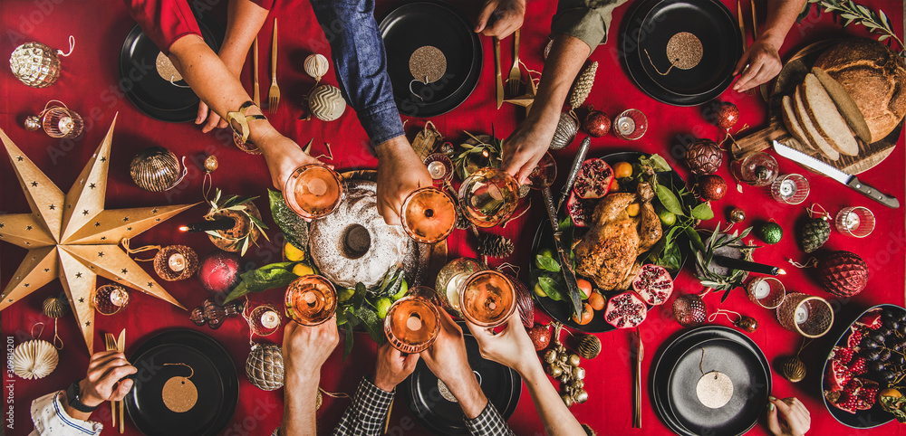 Friends celebrating Christmas. Flat-lay of people clinking glasses with rose wine over festive table