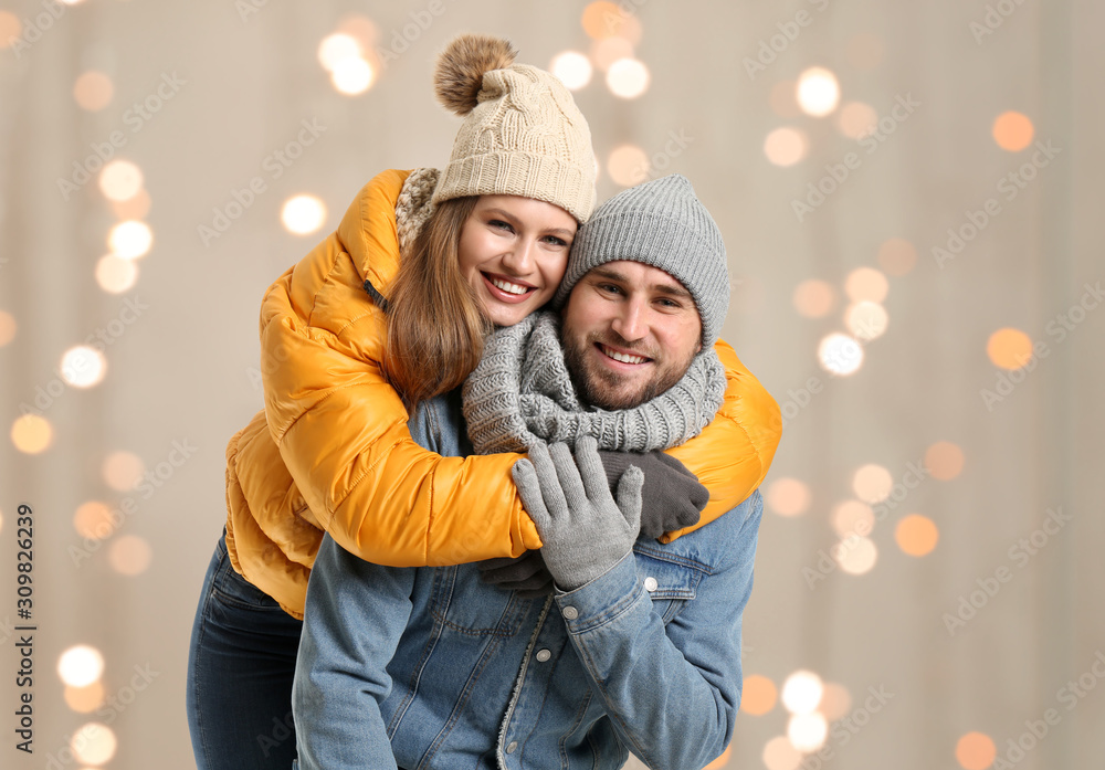 Portrait of happy couple in winter clothes against blurred Christmas lights