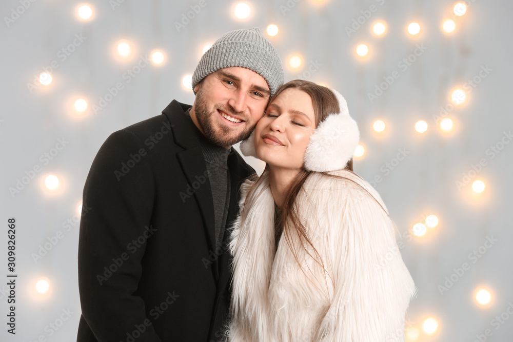 Portrait of happy couple in winter clothes against blurred Christmas lights