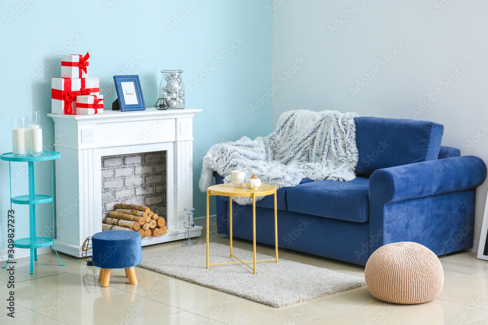 Comfortable blue sofa and fireplace in interior of living room