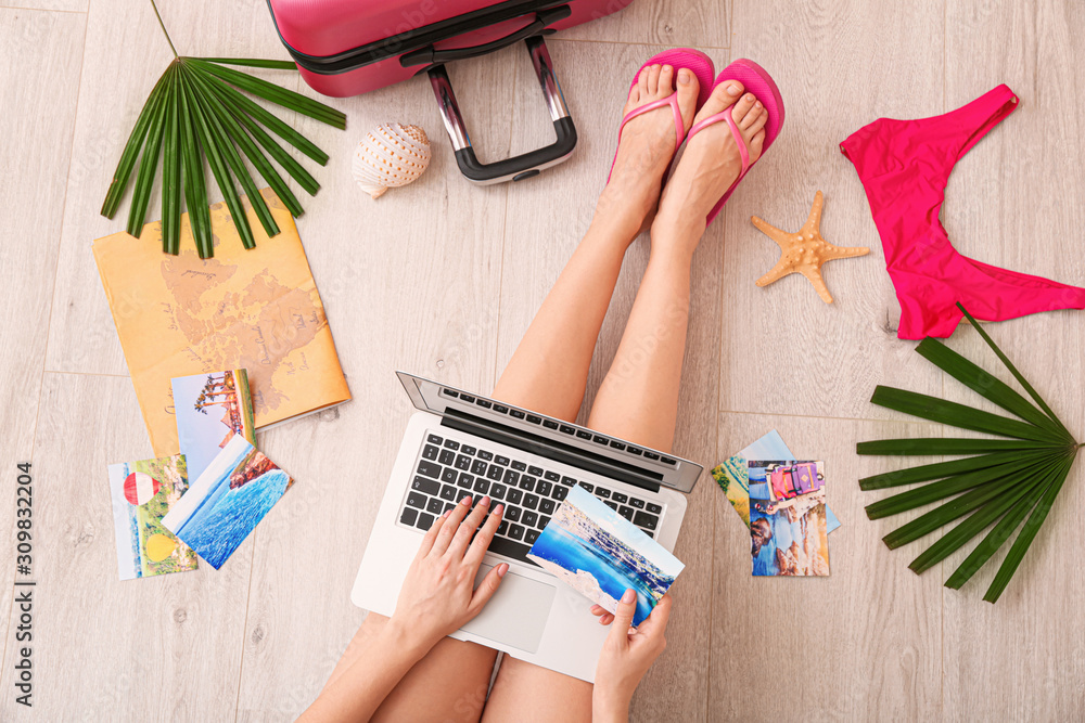 Woman with laptop visiting travel agency website, top view