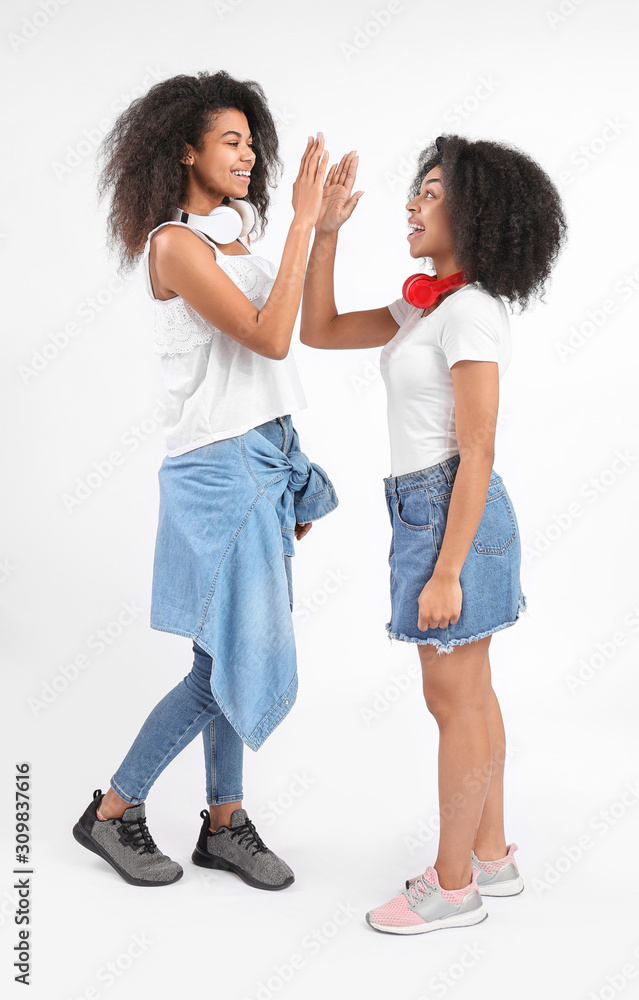 Portrait of young African-American women giving each other high-five on white background