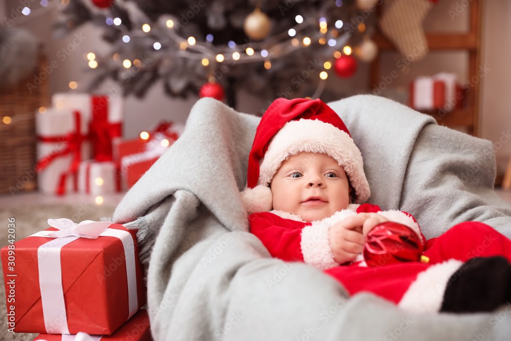 Cute little baby in Santa Claus costume at home