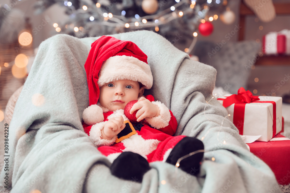 Cute little baby in Santa Claus costume at home