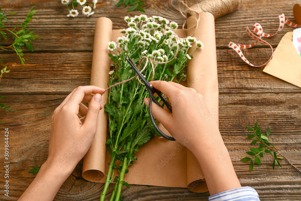 Female florist making beautiful bouquet on wooden background