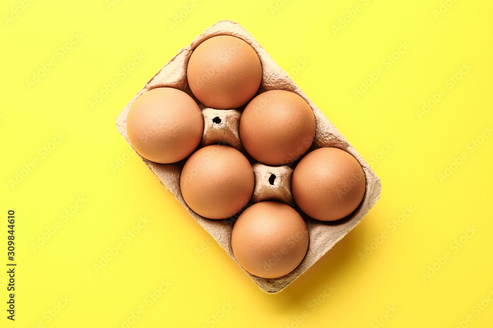 Package with fresh eggs on color background