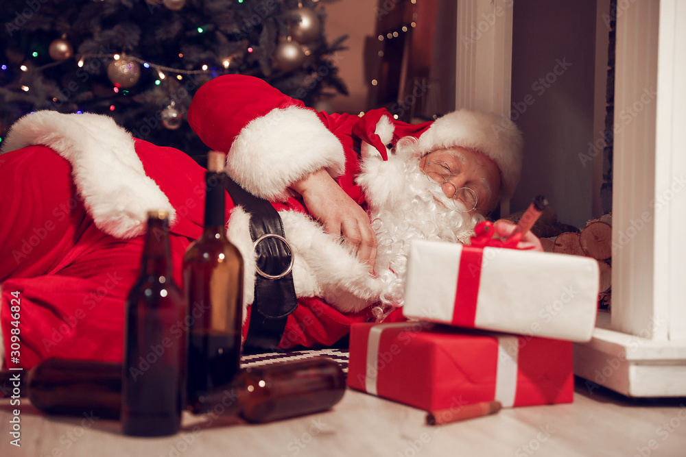 Funny drunk Santa Claus lying on floor near fireplace