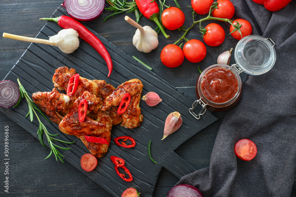 Tasty chicken wings with barbecue sauce on dark table