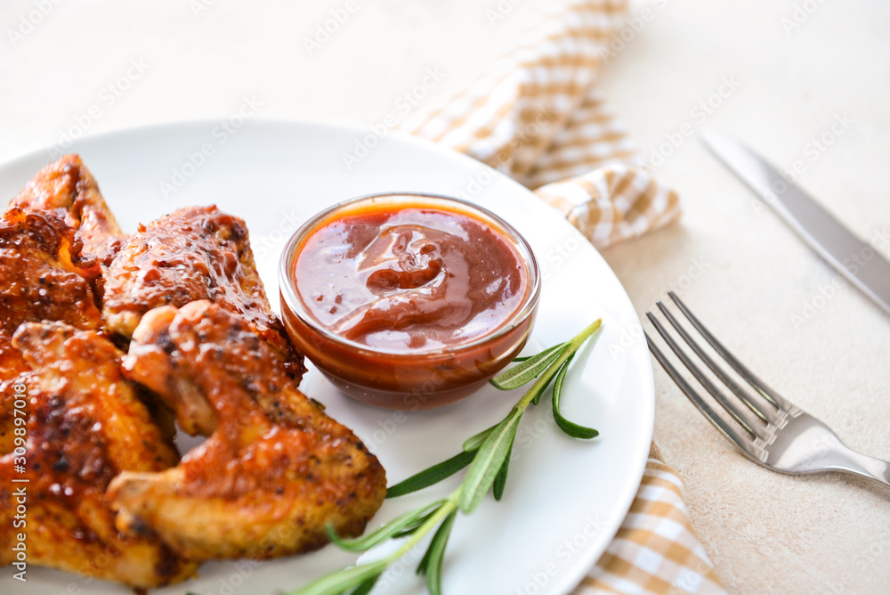 Plate with tasty fried chicken wings and barbecue sauce on white table