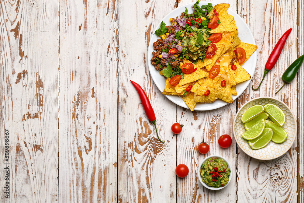 Plate with tasty chili con carne and nachos on table