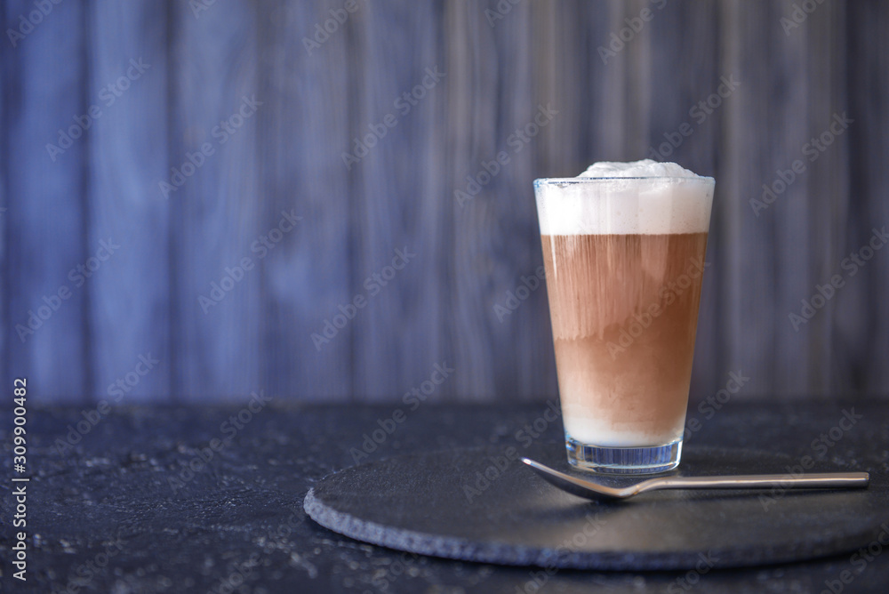 Glass of tasty latte on dark table